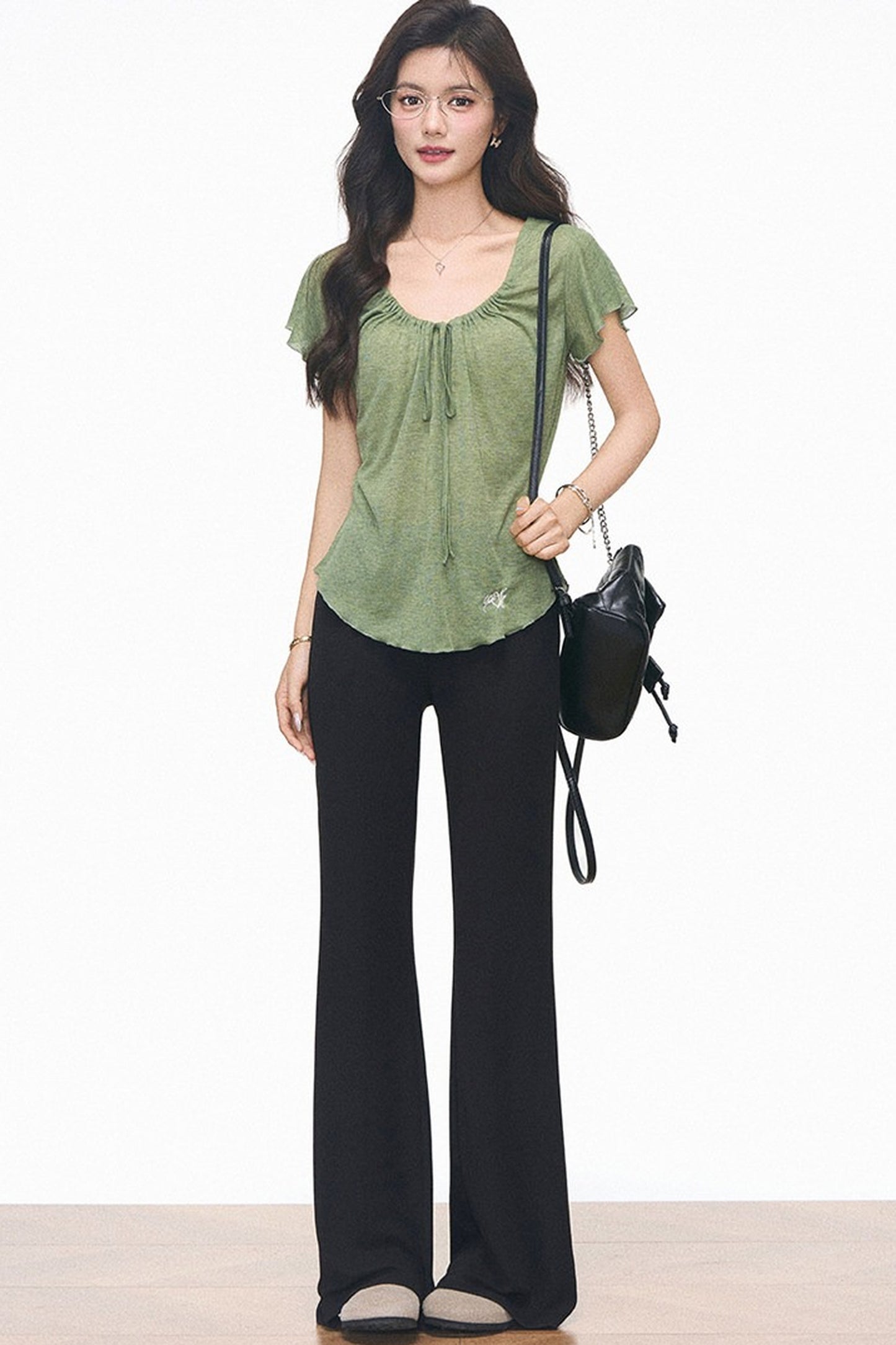 Completo con maglia verde con coulisse e pantaloni neri svasati