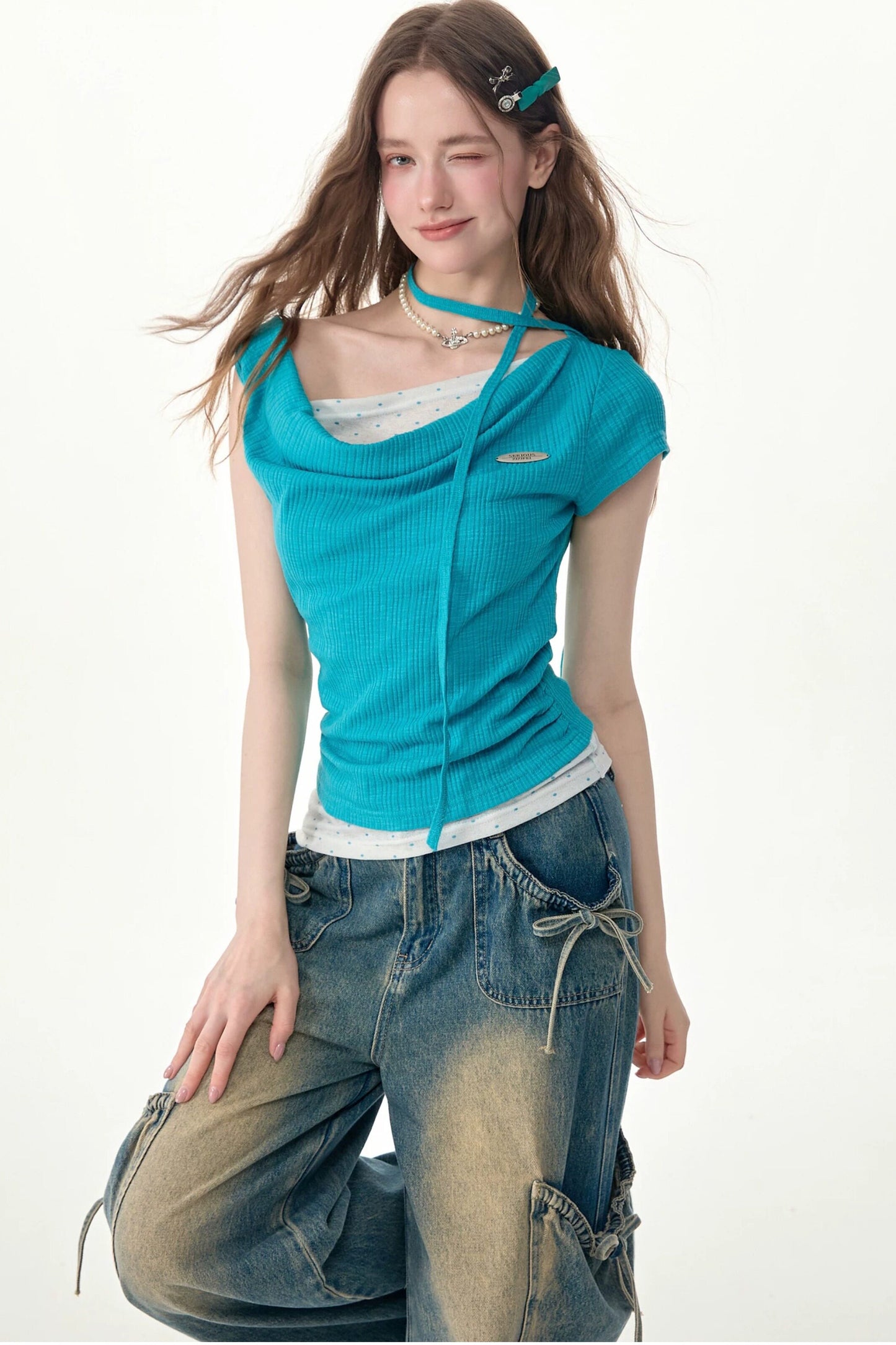 Top in maglia blu a pois con collo drappeggiato asimmetrico