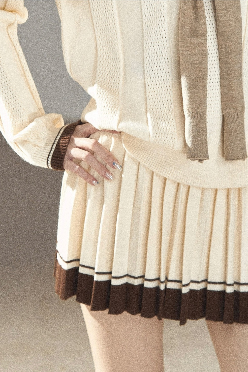 Completo con top a maglia, gonna corta plissettata e giacca