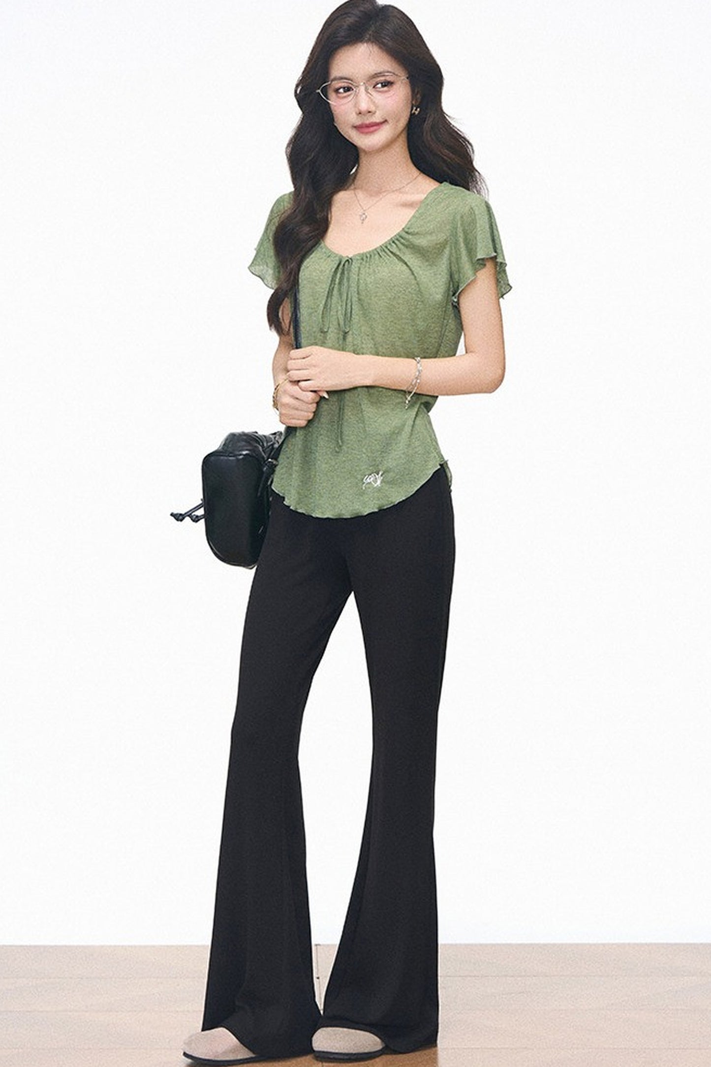 Completo con maglia verde con coulisse e pantaloni neri svasati
